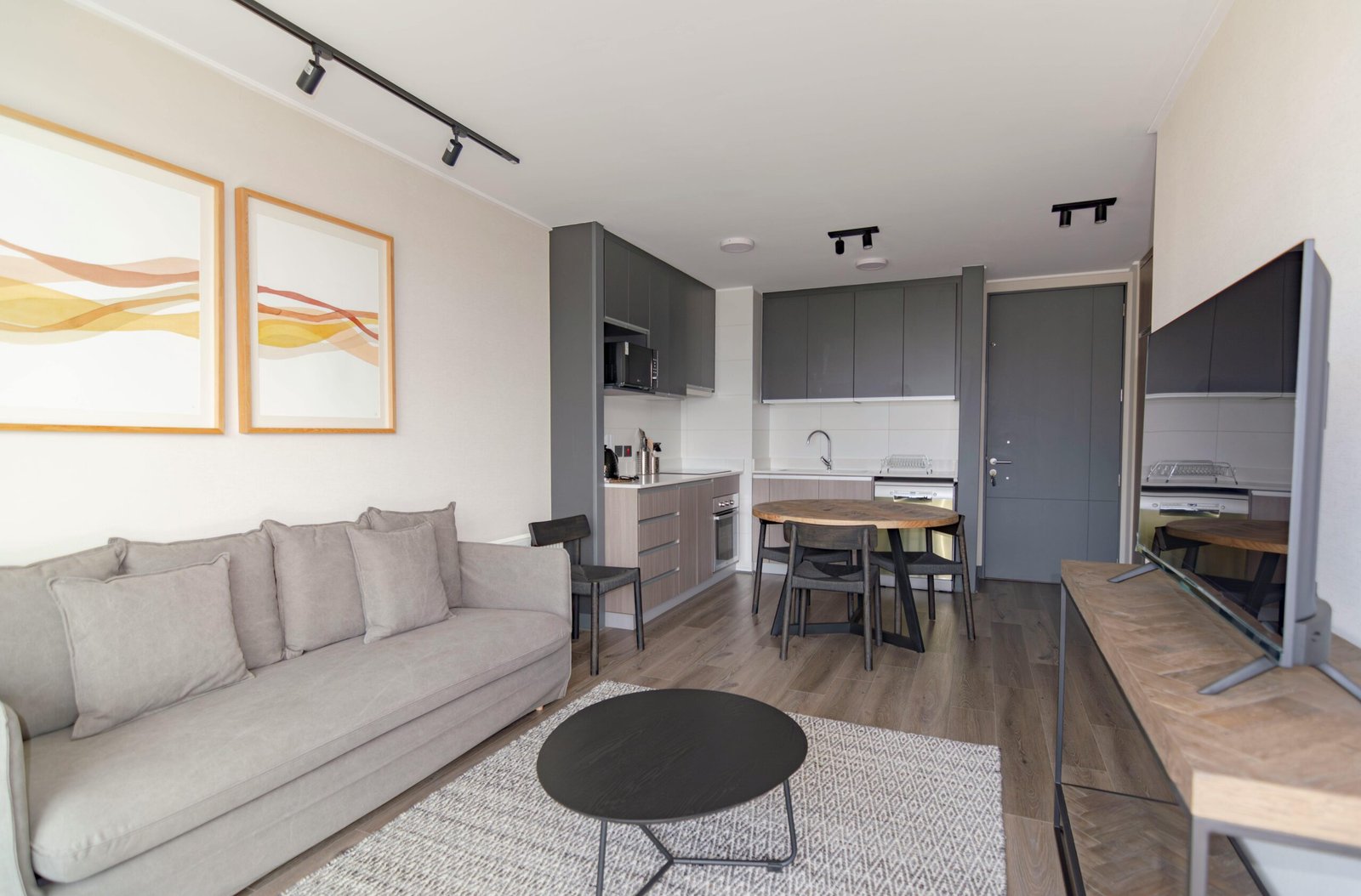 Home Elegant modern living space with grey couch, minimalist decor, and open kitchenette.